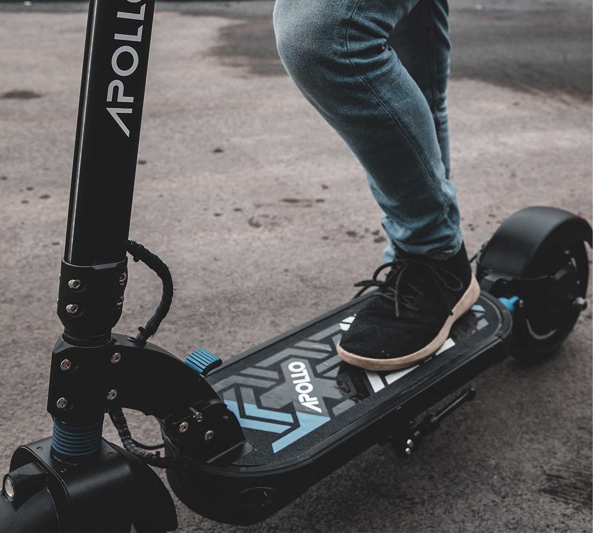 Close-up of a rider's feet on an 'APOLLO' electric scooter, highlighting the durable materials and construction that contribute to the longevity and lifespan of such personal electric vehicles.